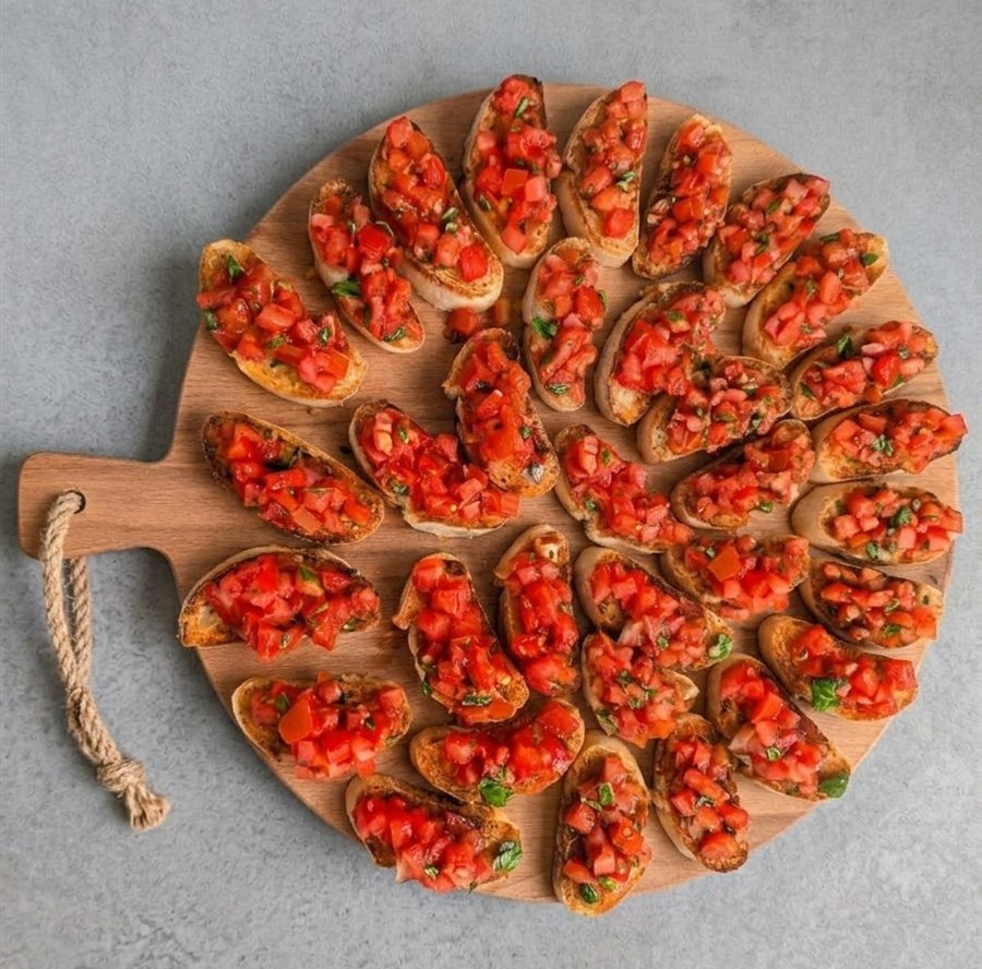 Verse bruschetta al Pomodoro met tomaat en basilicum op een houten plank