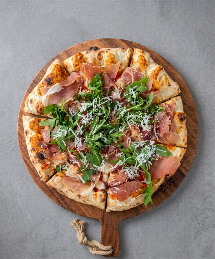 Pizza Prosciutto Crudo met rucola en Parmezaanse kaas op een houten plank